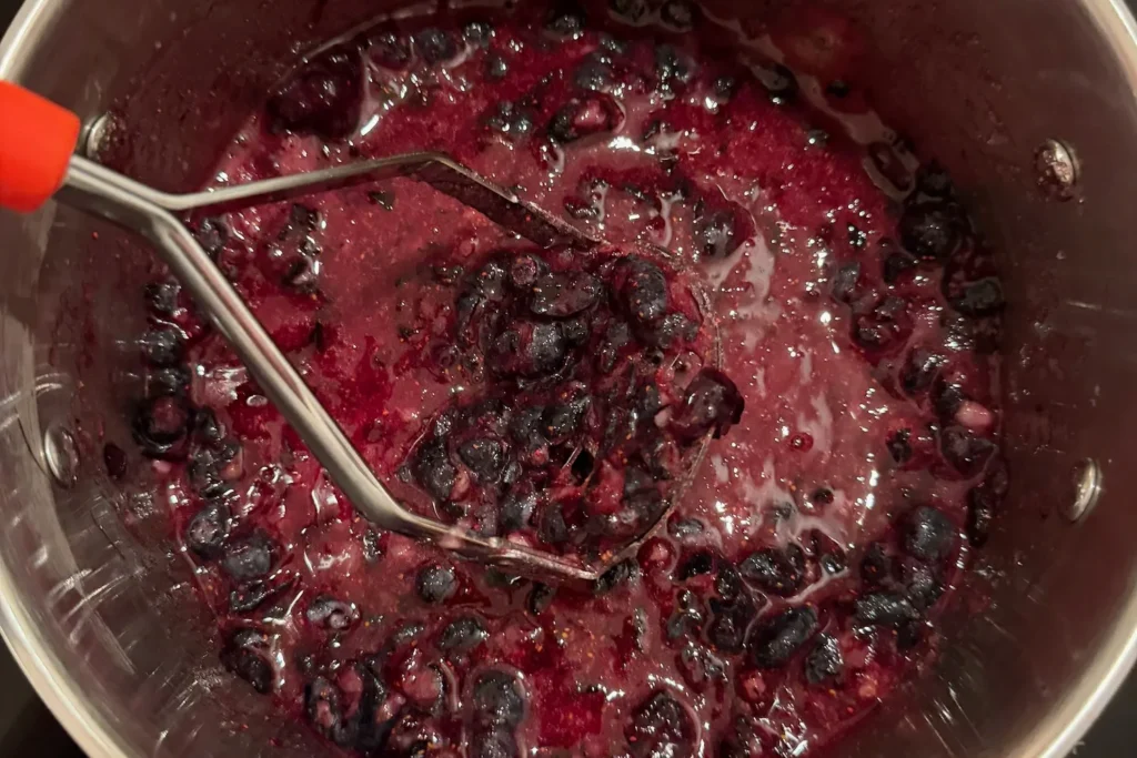 Heidelbeermarmelade kocht im Topf, die Früchte sind teilweise zerfallen.