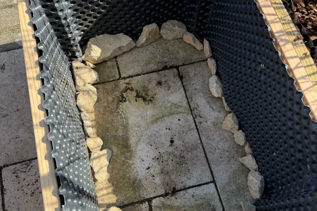 Hochbeet mit Noppenfolie ausgekleidet und Steinen als Drainagebegrenzung am Boden