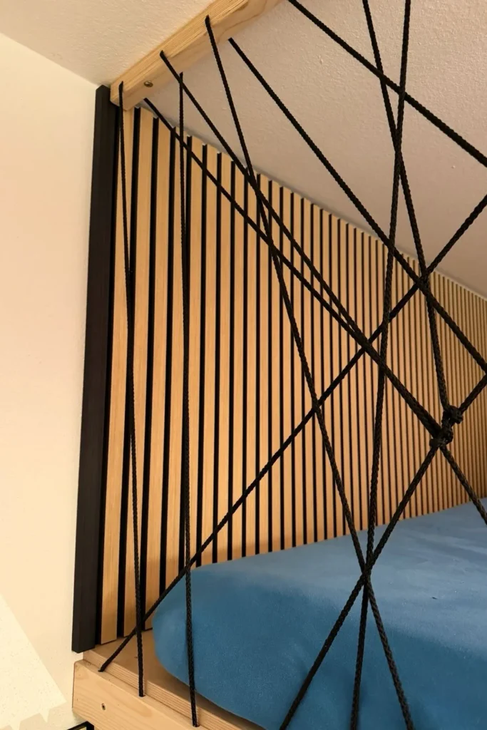Hochbett mit Akustikpaneelen im Hintergrund und Rausfallschutz aus Seilen.