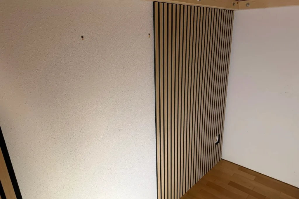 Montierte Akustikpaneele in Holzoptik als Wandverkleidung unter einem Hochbett.