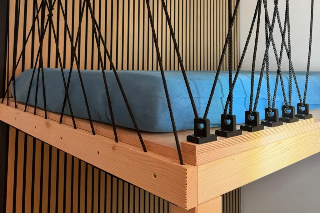 Nahaufnahme Rausfallschutz aus schwarzen Seilen an einem selbstgebauten Hochbett mit Holzrahmen.