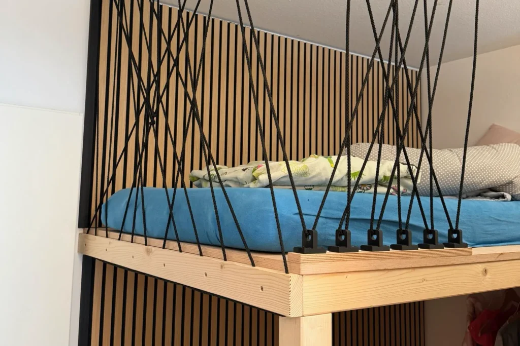 Nahaufnahme Rausfallschutz aus schwarzen Seilen an einem selbstgebauten Hochbett mit Holzrahmen.