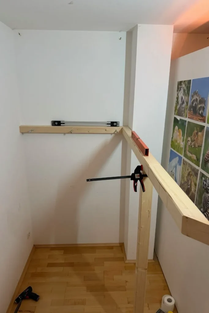 Montage der Unterkonstruktion eines Hochbetts mit Wandbalken, Pfosten und Schraubzwingen zur Ausrichtung.