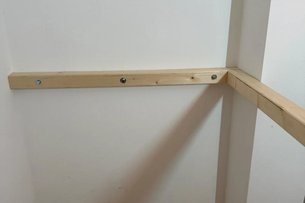 Waagrecht montierter Holzbalken eines Hochbetts mit Wandbefestigung und Sechskantschrauben.