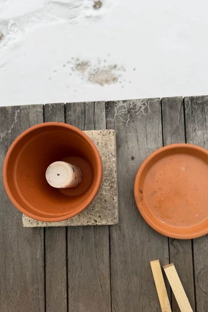 Materialien für eine frostfreie Wasserstelle für Vögel: Tontopf, Untersetzer und Kerze im Winter