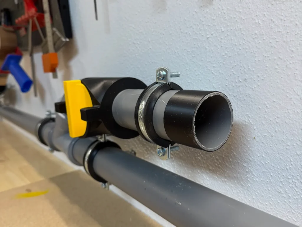 Zwischen Werkbank und Staubsauger montierter 67-Grad-Abzweig aus DN50 PP-Rohr zur Steuerung des Luftstroms in Richtung Staubsauger.