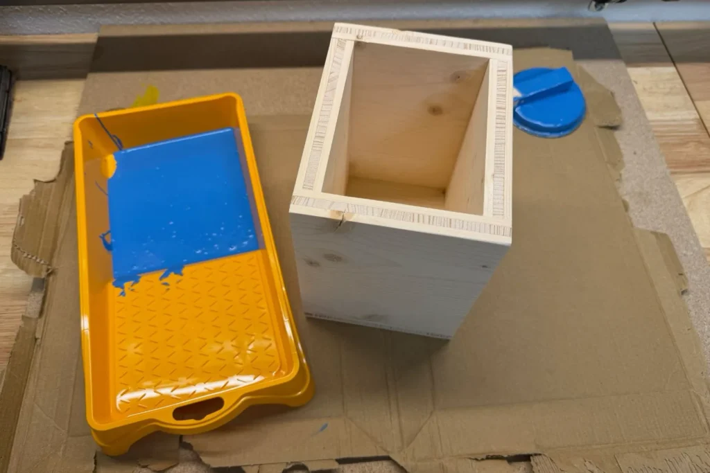 Farbwanne mit blauem Buntlack und Holzrahmen für Wildbienen-Nisthilfe