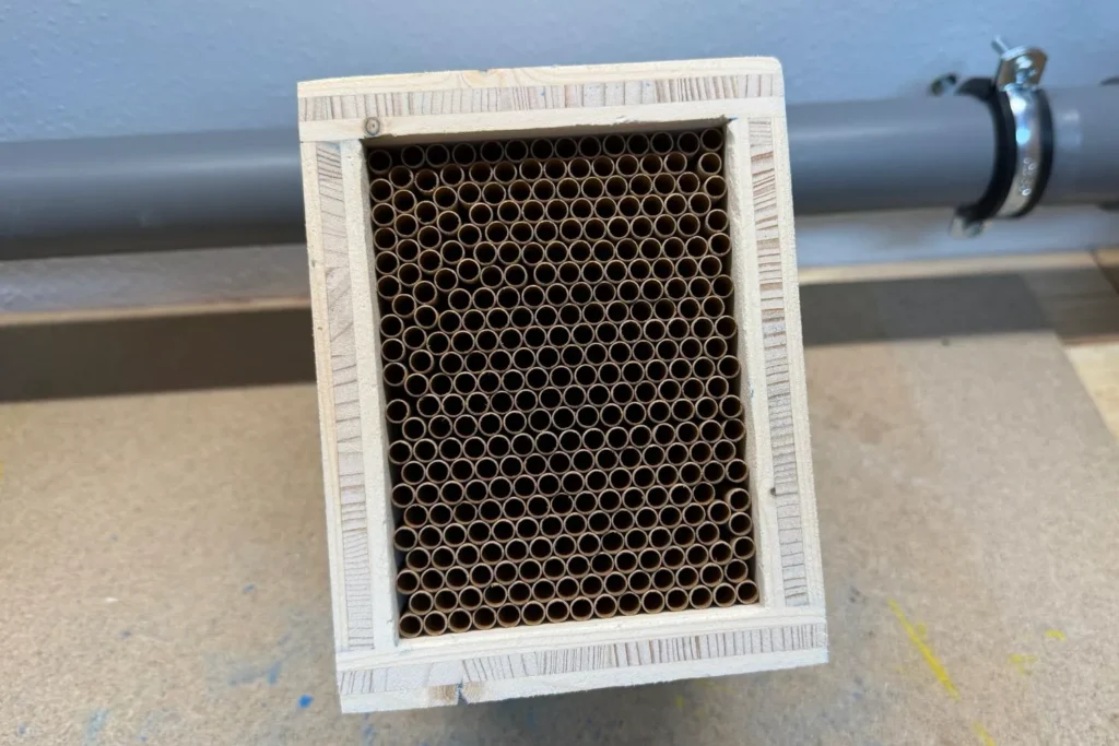 Fertig gebaute Wildbienen-Nisthilfe mit vollständig eingesetzten Nisthülsen in der Frontansicht