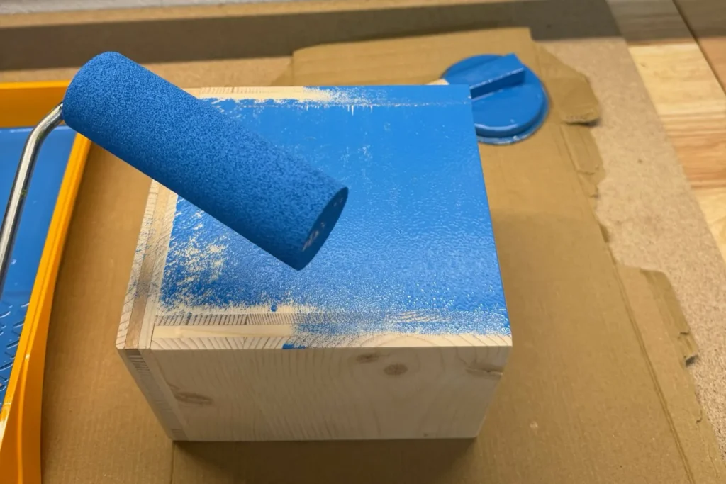 Die Außenseiten der Wildbienen-Nisthilfe werden mit wasserbasierter Farbe gestrichen.