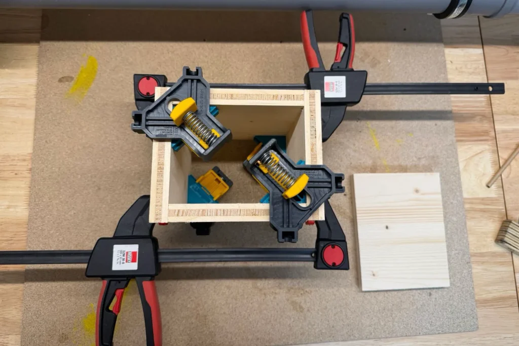 Der Rahmen der Wildbienen-Nisthilfe wird mit Schraubzwingen fixiert, während der Holzleim aushärtet