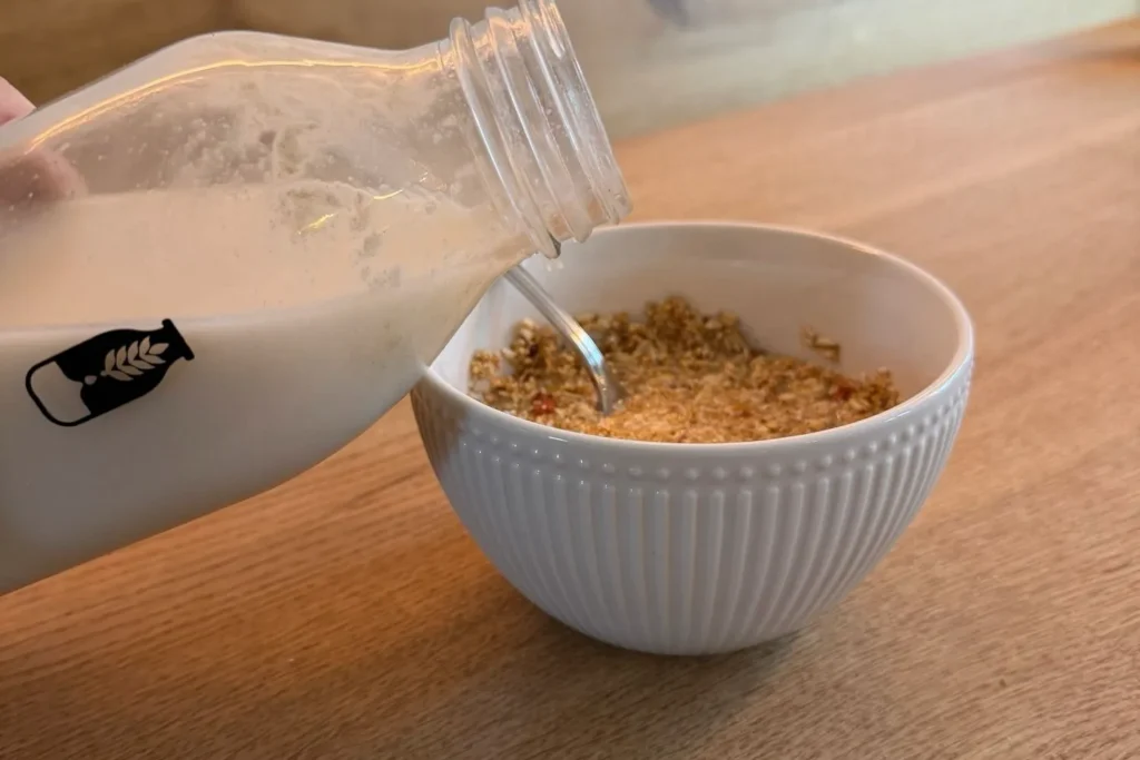 Frisch zubereitete Hafermilch aus dem Mylky Pflanzenmilch-Maker wird über ein Amaranth-Müsli gegossen