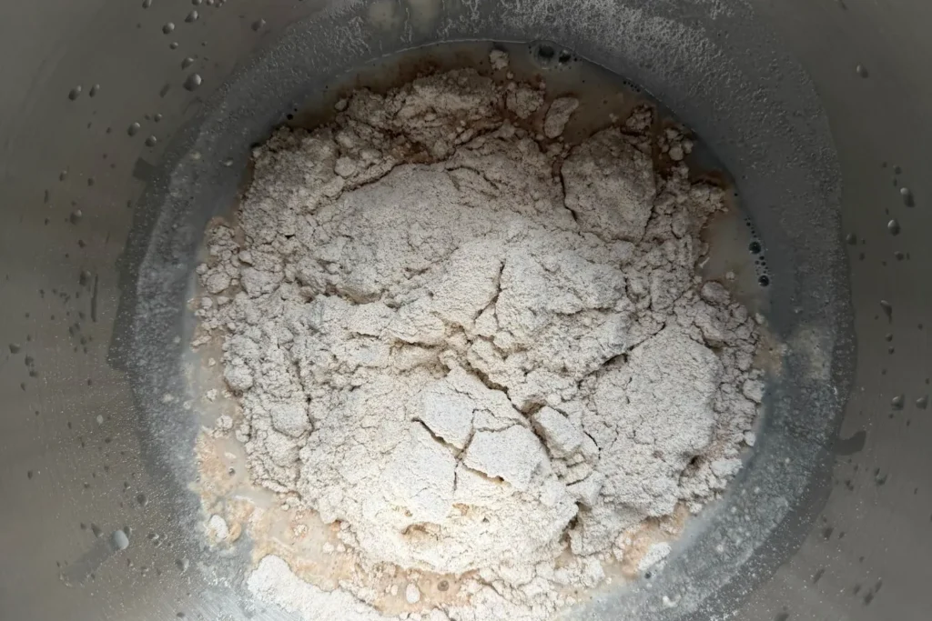 Dinkelvollkornmehl wird auf aufgelöstes Anstellgut im Wasser gegeben