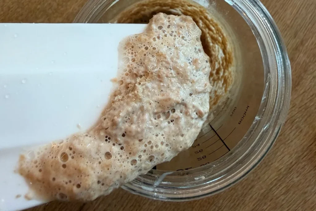 Aktiver Sauerteig mit Bläschen und deutlich aufgegangenem Volumen im Glas
