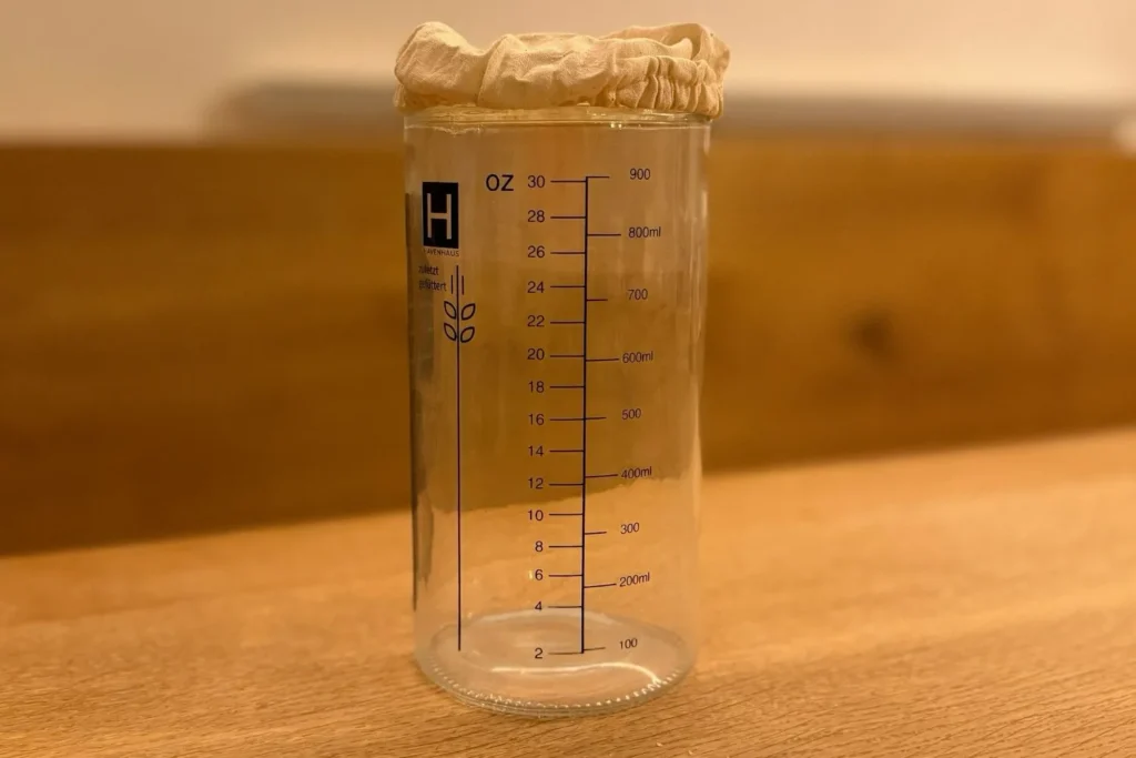 Sauberes Glas mit Markierungen für Sauerteig Starter auf der Küchenarbeitsplatte