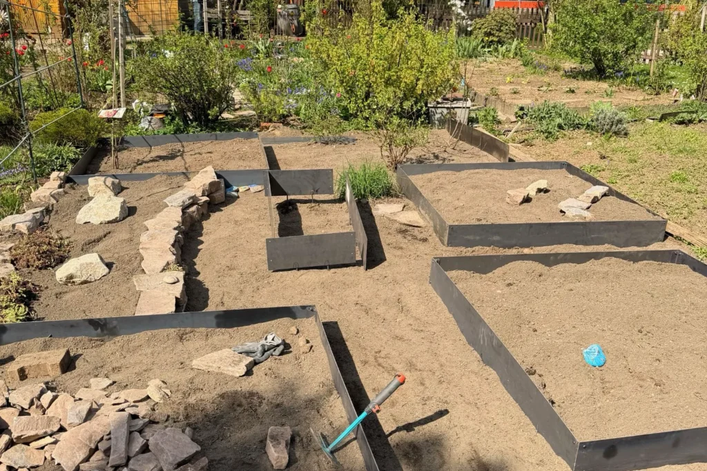 Mehrere neu montierte Cortenstahl-Beeteinfassungen im Schrebergarten vor der Bepflanzung