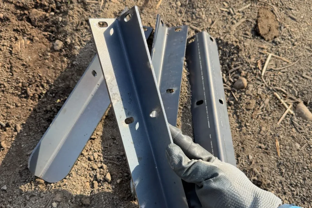 Mehrere Cortenstahl-Eckverbinder liegen auf Erde vor der Montage