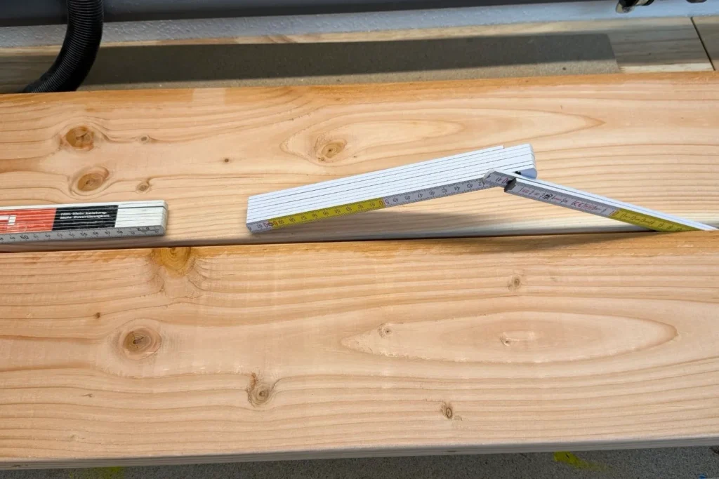 Zollstock wird als Abstandshalter zwischen Holzbrettern beim Hochbeet Bau verwendet