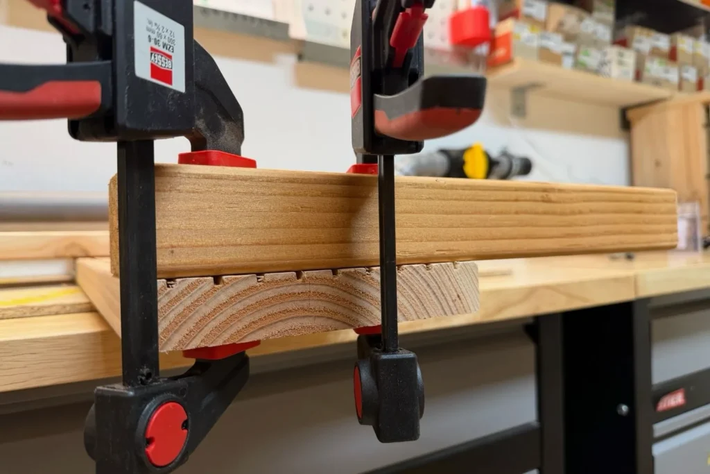 Erstes Brett wird mit Einhandzwingen für den Hochbeetbau fixiert