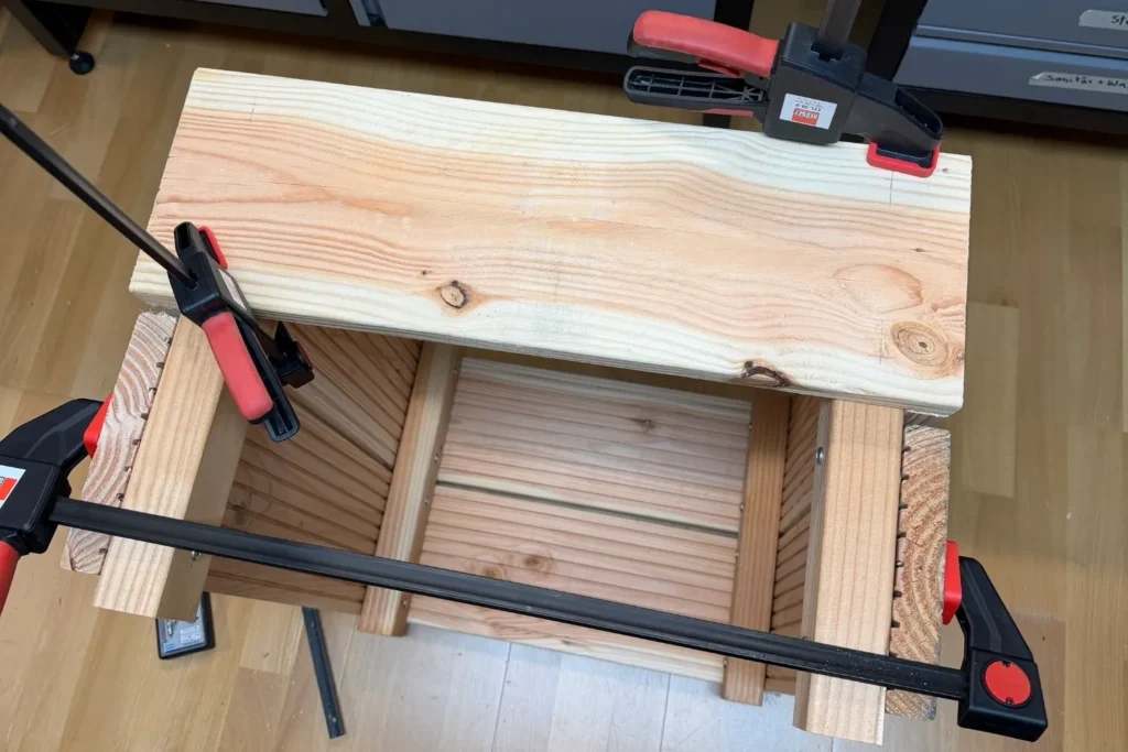 Letzte Bretter eines Hochbeets werden mit Schraubzwingen fixiert und montiert