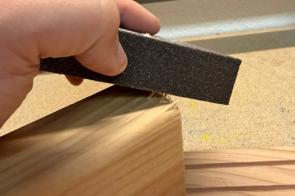 Holz wird mit Schleifschwamm bearbeitet, um scharfe Kanten zu glätten