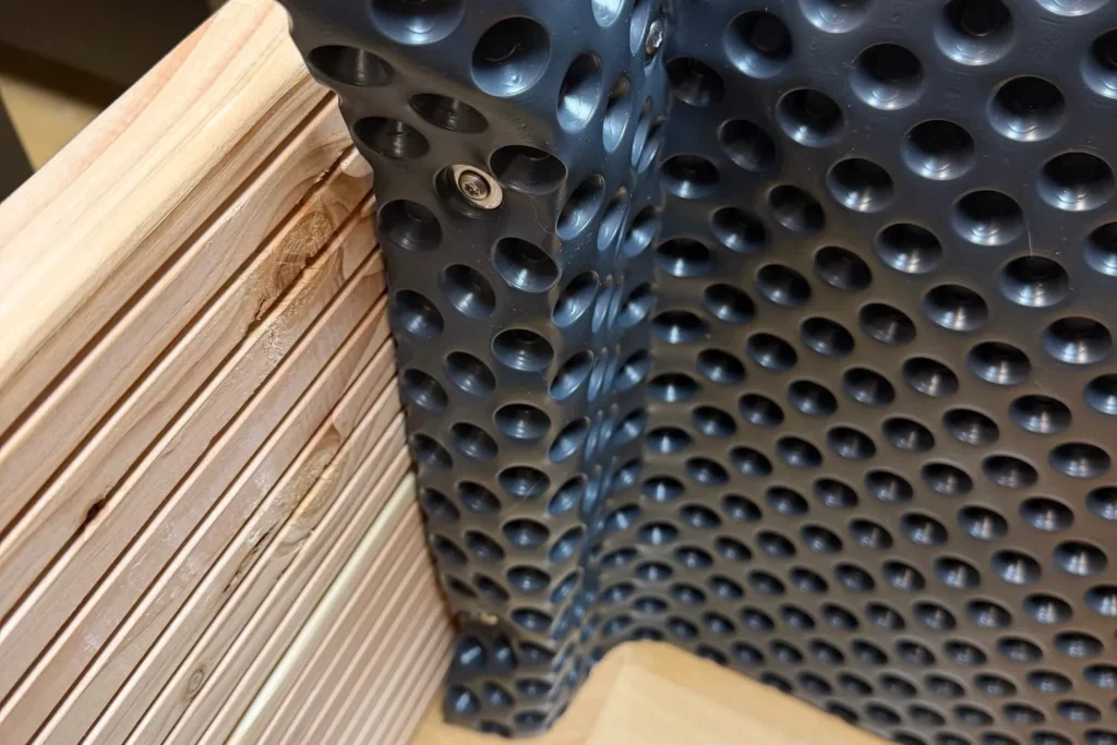 Noppenfolie wird in der Ecke eines Hochbeets sauber verschraubt