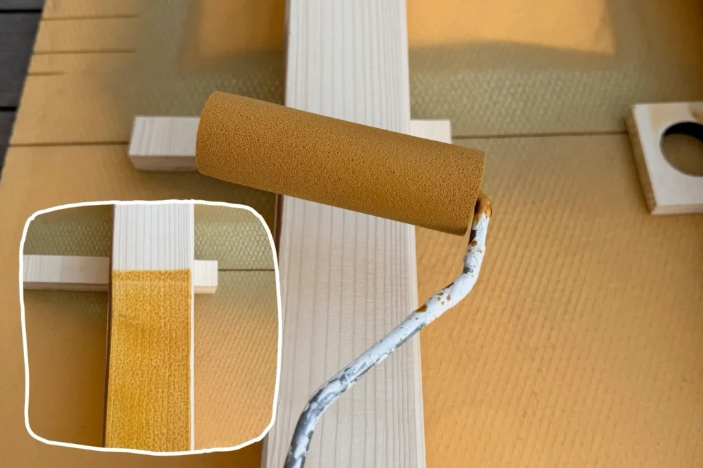 Holzschutzlasur wird mit Lackrolle auf Kantholz für Rankhilfe aufgetragen