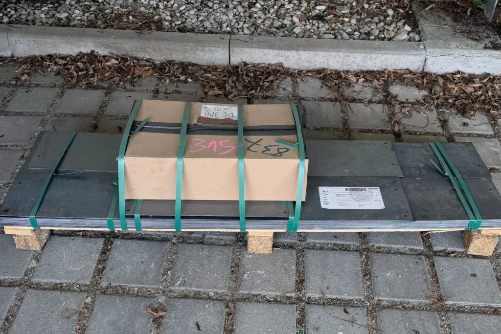 Gelieferte Cortenstahl-Beeteinfassung als gebündeltes Paket auf Pflastersteinen
