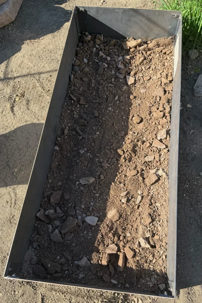 Erste Schicht mineralisches Magersubstrat im Cortenstahlrahmen für ein neues Magerbeet.