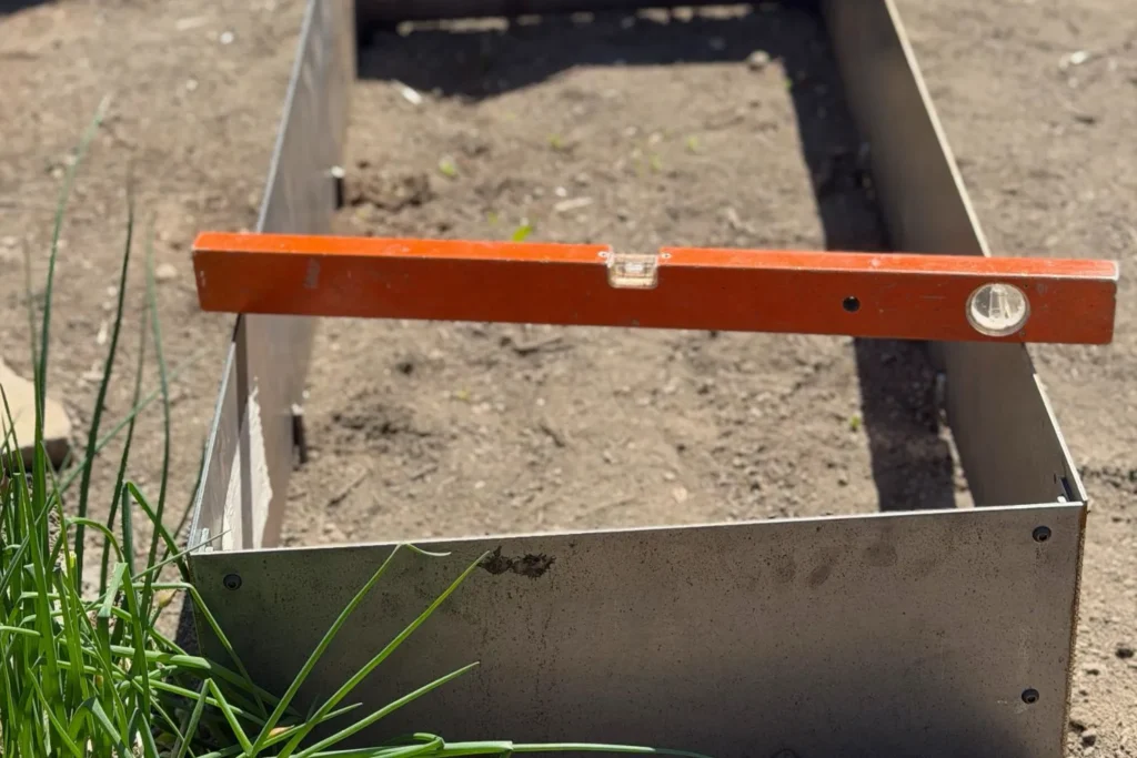 Wasserwaage auf Cortenstahlrahmen beim Aufbau eines Magerbeets