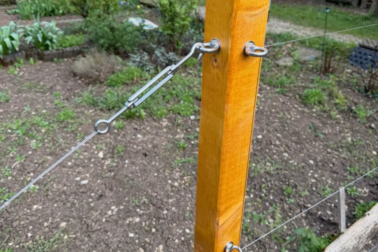 Straff gespannte Edelstahlseile einer Rankhilfe aus Holz in Nahaufnahme