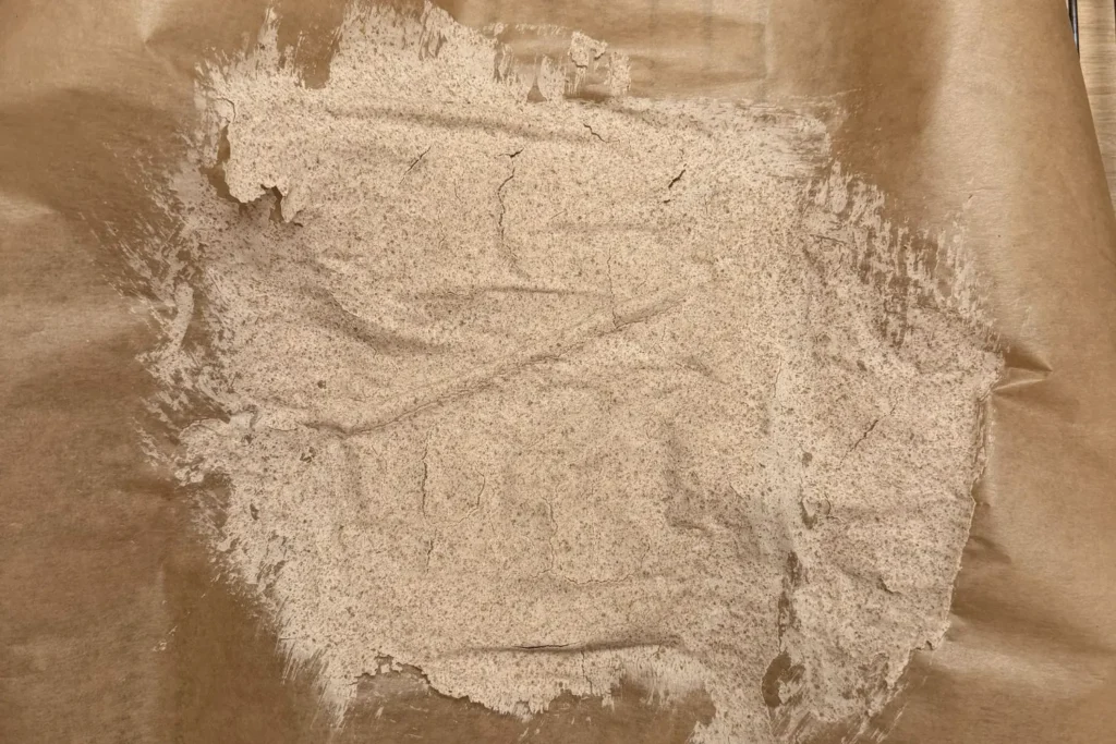 Vollständig getrockneter Sauerteig auf Backpapier mit rissiger Oberfläche
