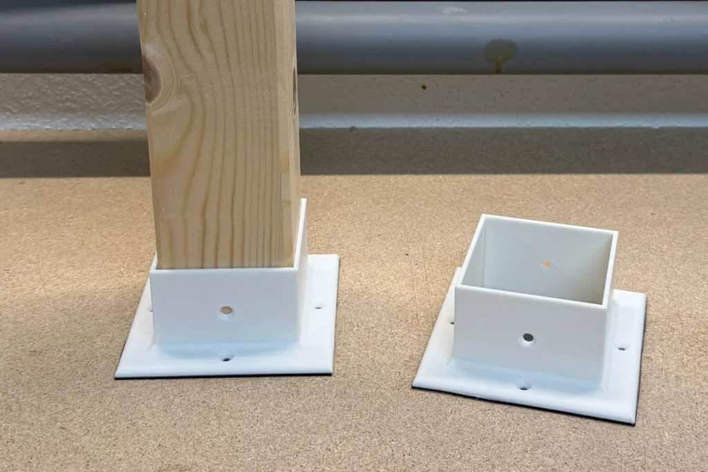 Kantholz steckt in einem 3D-gedruckten Pfostenschuh mit EPDM-Unterlage.