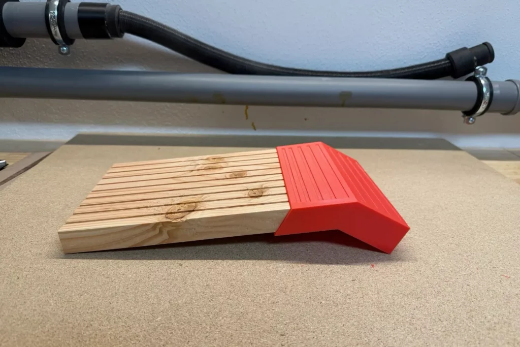 Ein Holzbrett wird in einen roten PETG-Winkel für eine Ausstiegshilfe eingesetzt