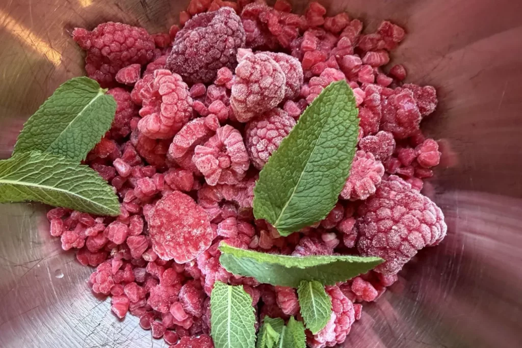 Tiefgekühlte Himbeeren und frische Minze für gesundes Himbeereis