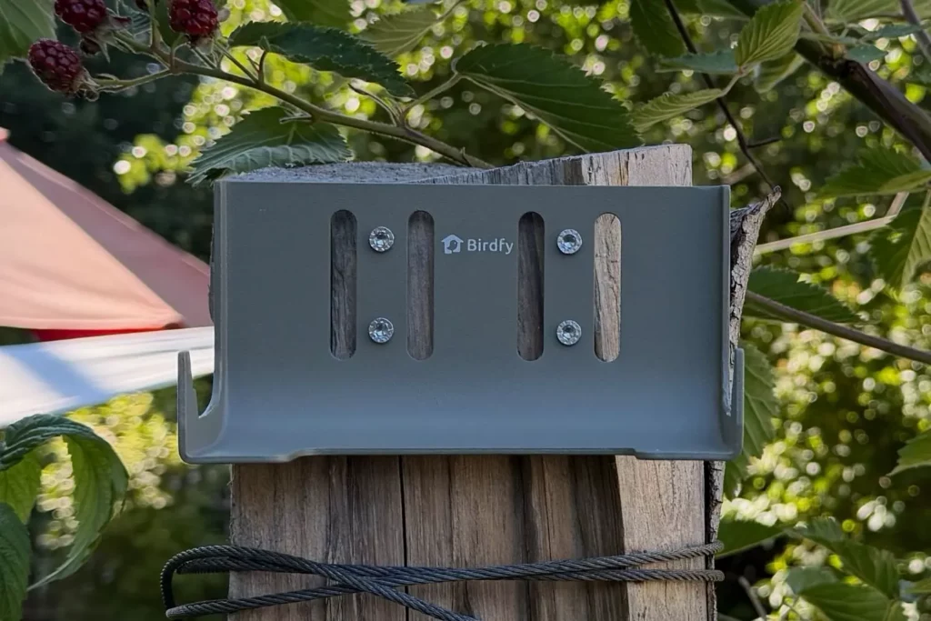 Wandhalterung des Birdfy Feeder Metal 2 4K an einem Holzstamm montiert.